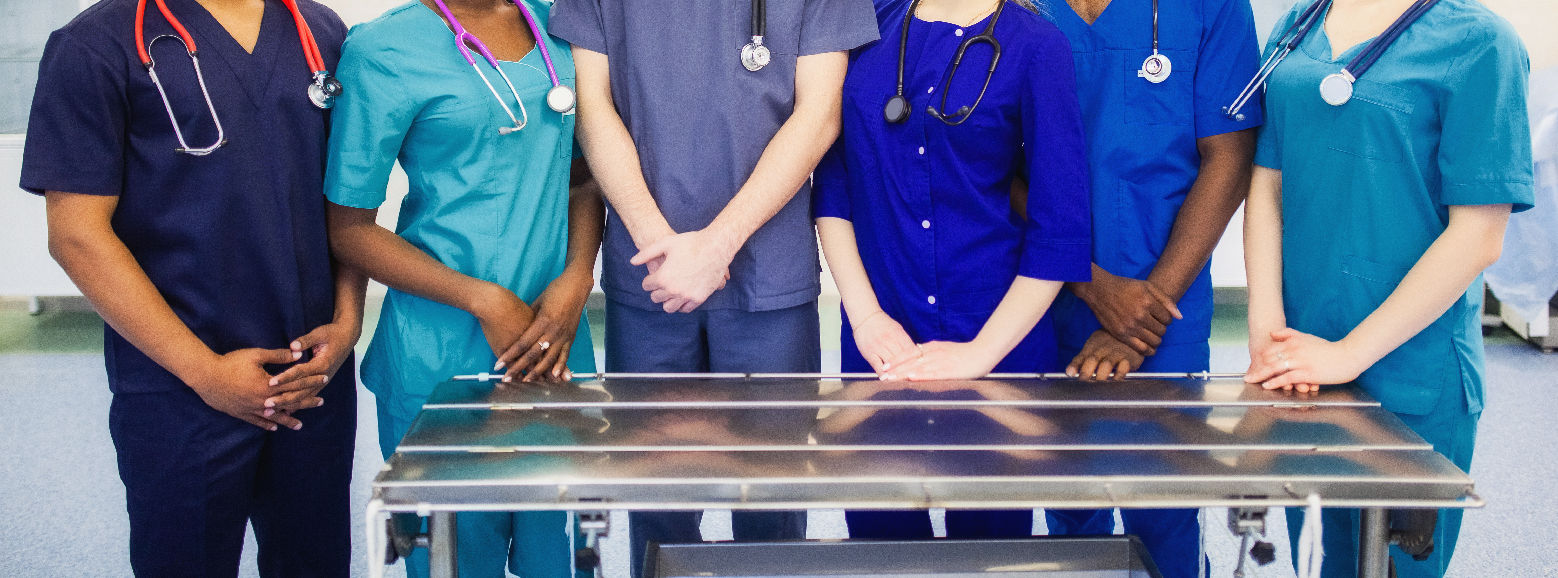 Medical and dental practitioners standing behind a metal counter.